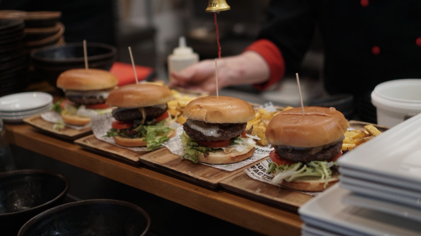 Burgers plated on a restaurant kitchen pass