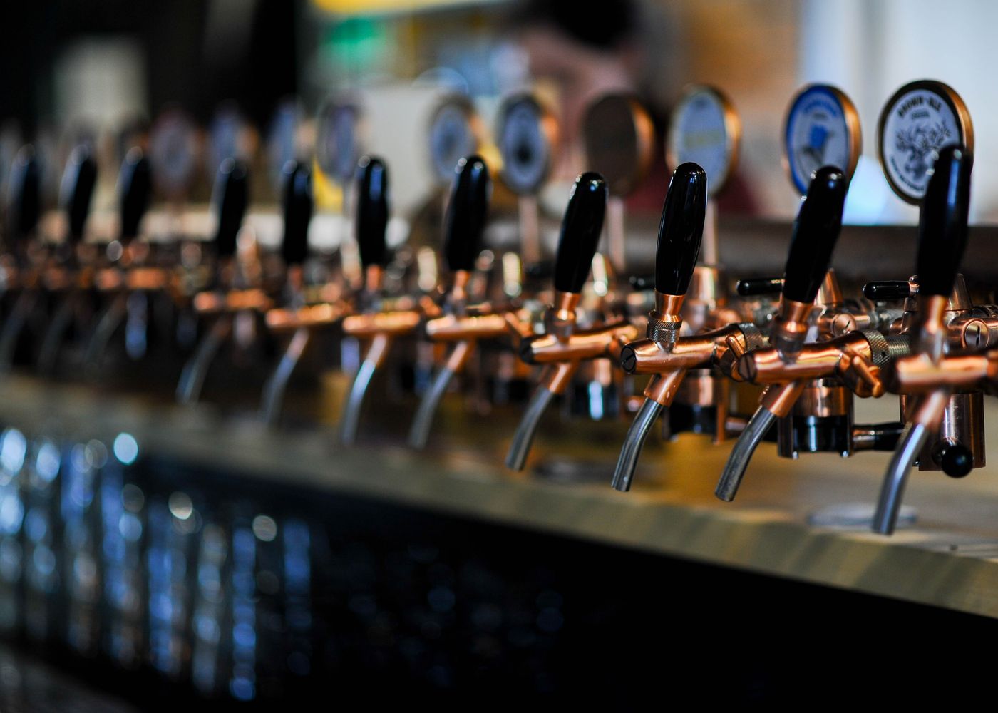 Row of copper craft beer taps along a bar counter