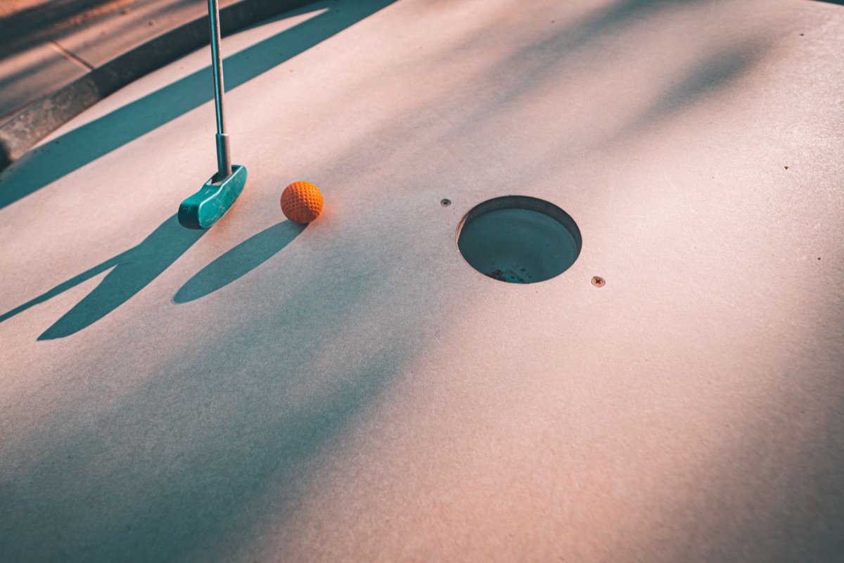 Putter and ball near a mini-golf hole