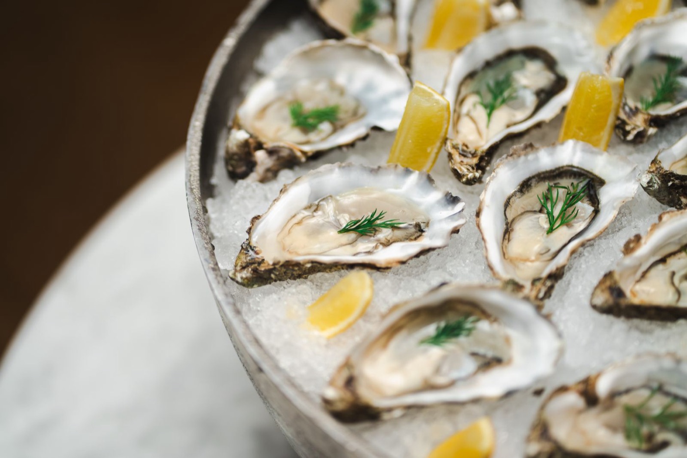 Platter of fresh oysters on ice with lemon and dill