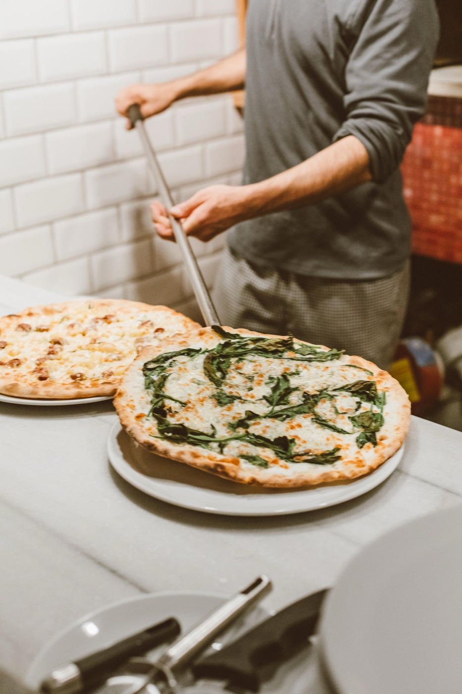 Pizzaiolo finishing a pizza in a restaurant kitchen